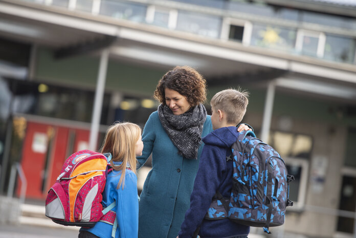 Mutter holt ihre zwei Schuldkinder ab.