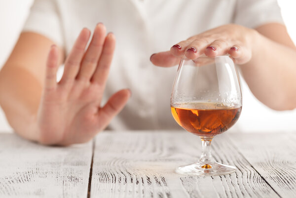 Ein Frau lehnt mit der Hand ein Glas Alkohol ab.