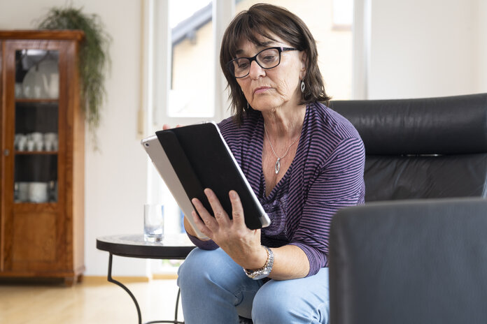 Eine Frau schaut auf den Bildschirm eines Tablets.