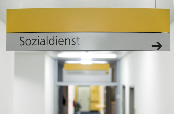 Schild an der Decke eines Krankenhaus-Flurs mit der Aufschrift Sozialdienst