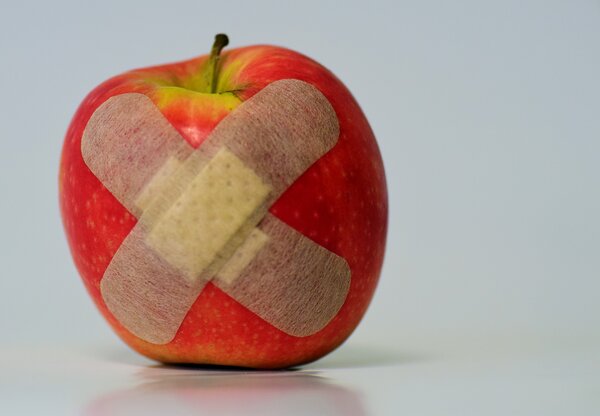Auf einem Apfel kleben zwei Pflaster.