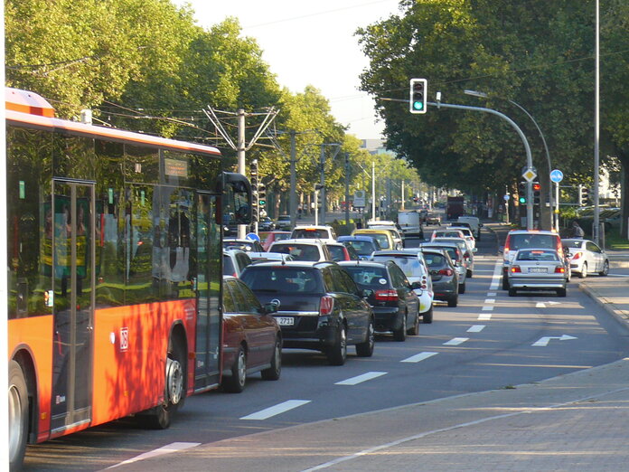 Mehrere Autos und ein Bus stehen vor einer Ampel.