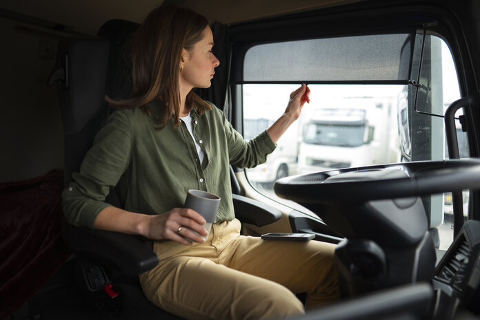 Frau im Auto schützt sich vor der Sonne mit einem Scheibenrollo