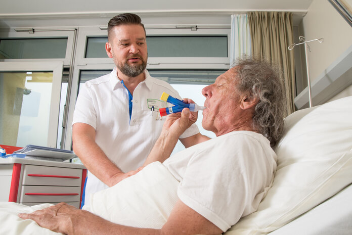 Ein Patient im Krankenhausbett beim Atemtraining.