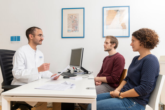 Ein Mann und eine Frau sitzen einem Arzt bei der Sprechstunde gegenüber.