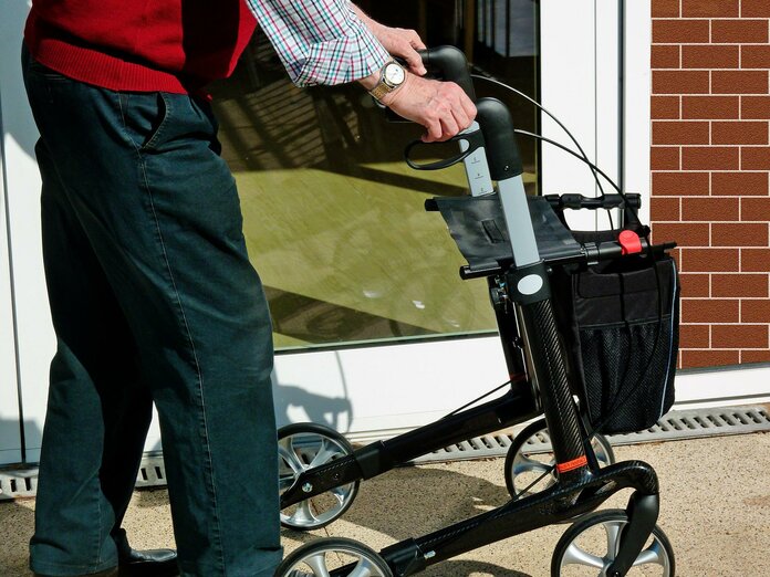 Mann schiebt Rollator