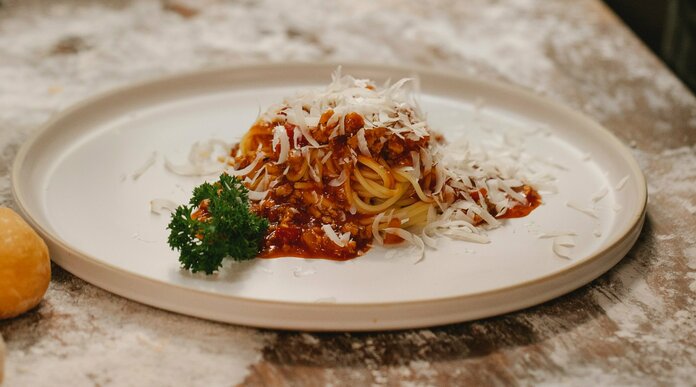 Eine kleine Portion Nudeln mit Sauce auf einem großen weißen Teller.