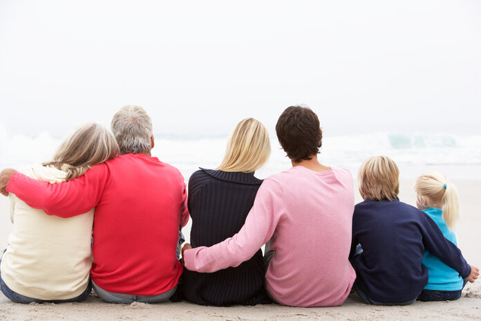 Familie aus drei Generationen sitzt am Strand